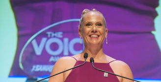 Kristy standing at a podium at the voice awards