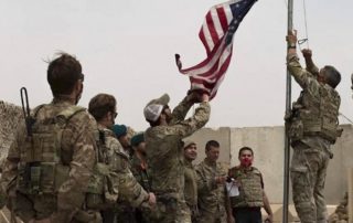 Troops pulling an American flag up on a flag pole