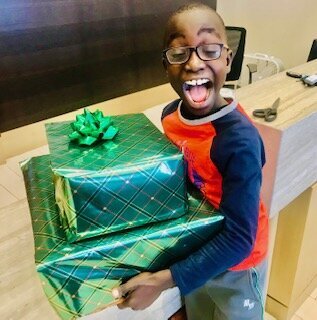 smiling boy holding a Christmas present excited to open them