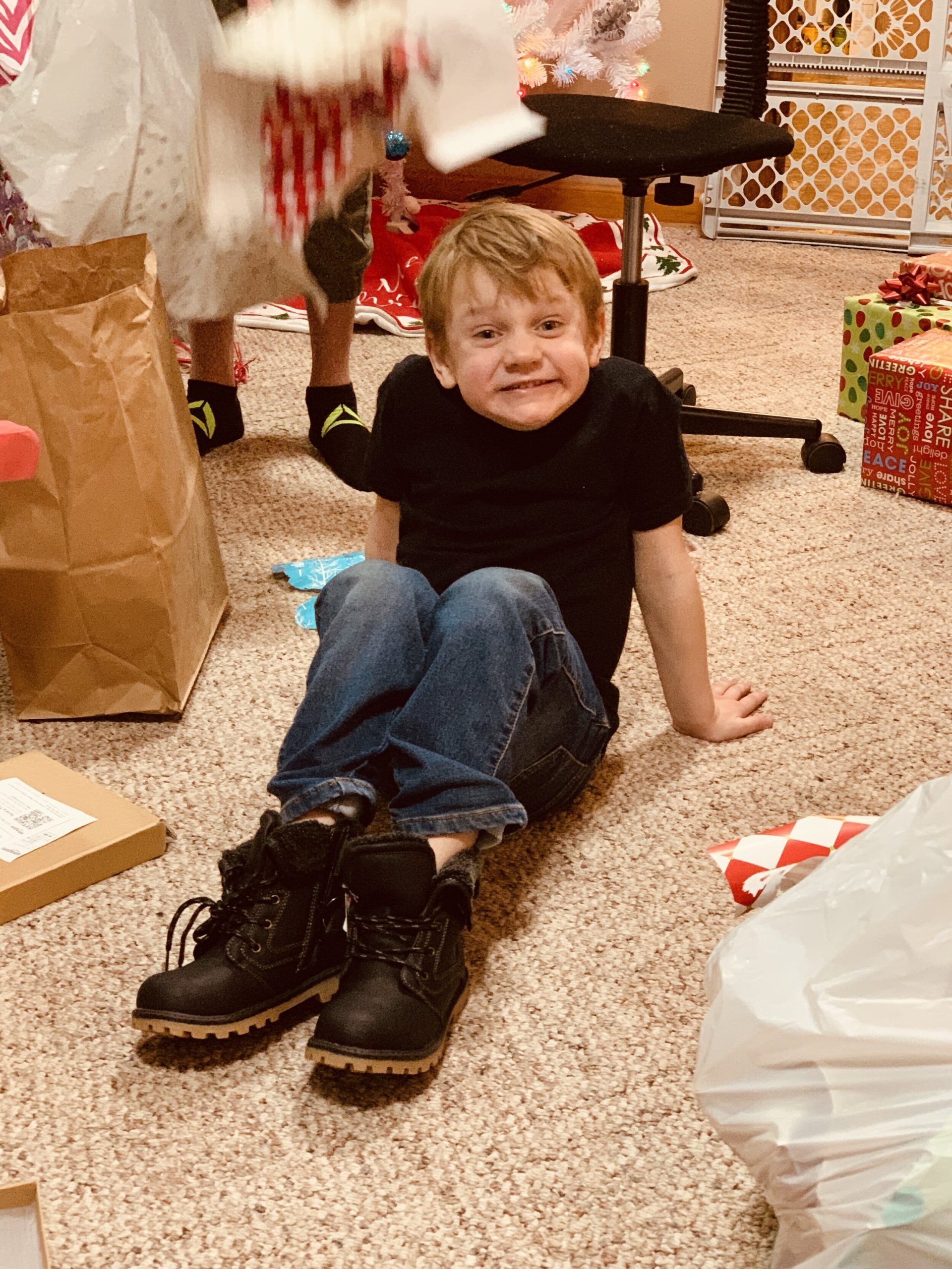 A little boy sitting on the ground wearing new shoes that were a Christmas present