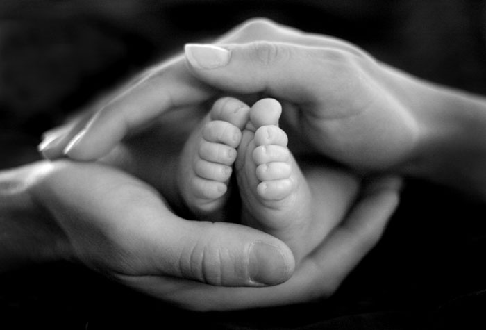 Parents holding the feet of a newborn
