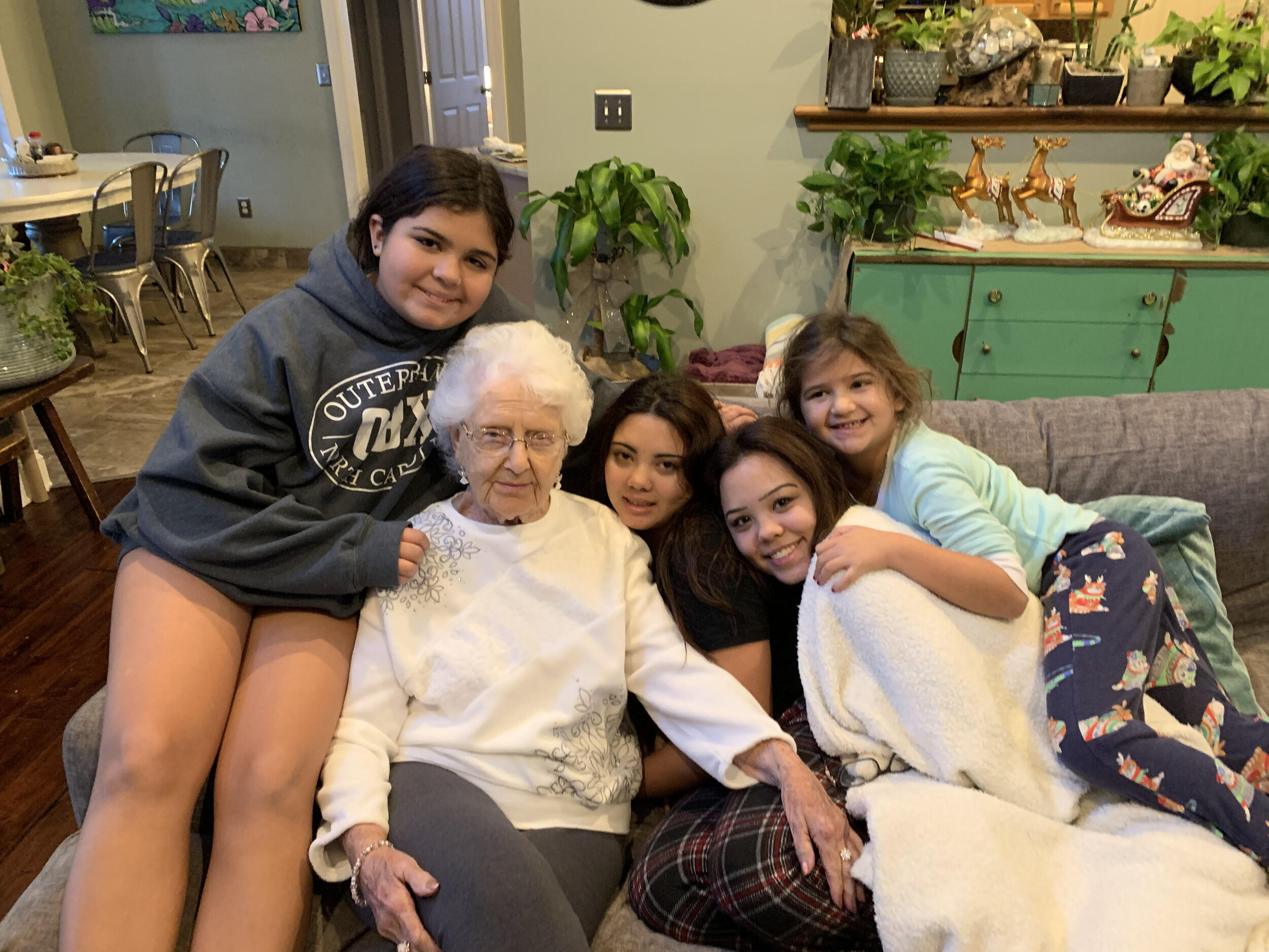 granddaughters smiling on the couch with their grandmother