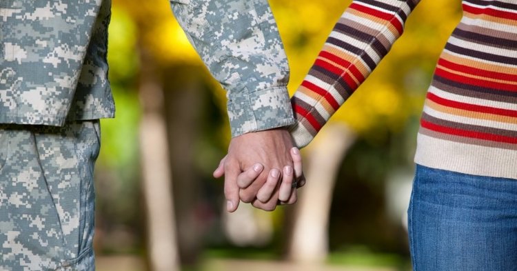 A woman and a man in uniform holding hands